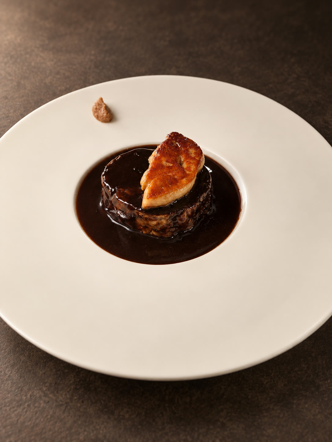 Composition sombre au centre d’une assiette blanche